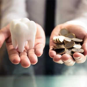 Person holding a tooth in one hand and coins in the other