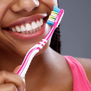 Close up of woman holding a toothbrush and smiling