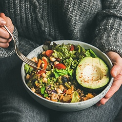 Person holding a bowl of healthy food and a fork