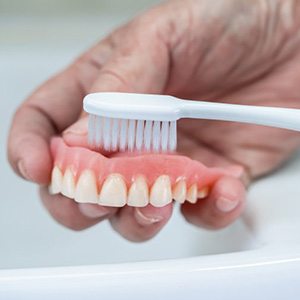 Someone brushes denture