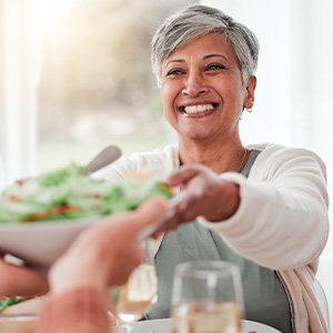 Woman smiling while grabbing bowl of salad
