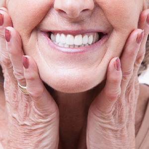 Close up of woman smiling and pressing her hands to her face