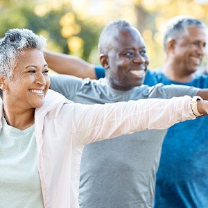 Group of adults smiling while stretching in park