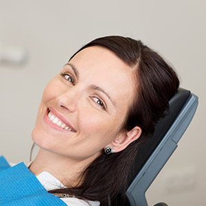 Woman with porcelain veneers smiling in dental chair