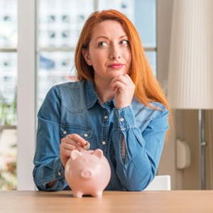 Woman putting a coin into a piggy bank