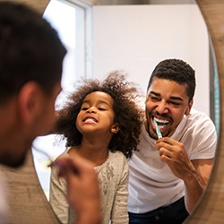 Father and daughter brushing their teeth