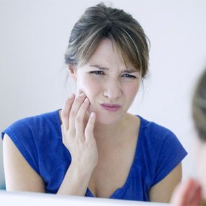 woman holding her cheek in pain  