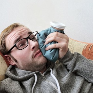 man holding a cold compress to his cheek   