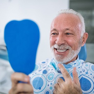 Man admiring his new dental implants in a mirror