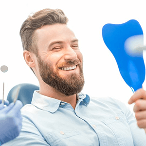 a patient checking his smile makeover in a mirror