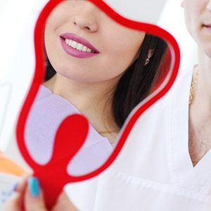 Patient with dental bridge looking at smile in mirror