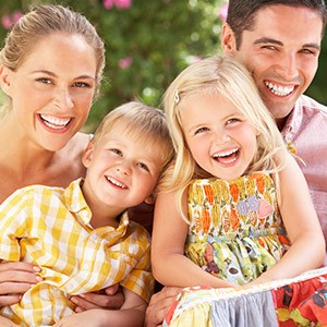 Mother father and two children smiling together after preventive dentistry