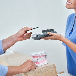 Patient using card to pay for treatment at dental office front desk