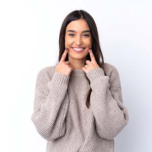 Woman pointing to smile after porcelain veneer placement