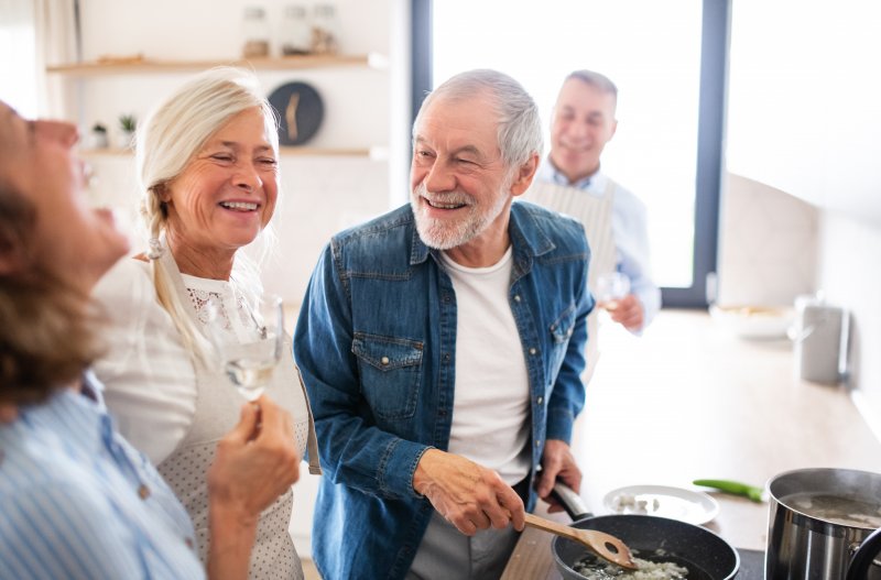 An older man socializing with his family in his new dentures while cooking