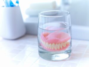 Dentures in a glass of clear liquid on bathroom counter